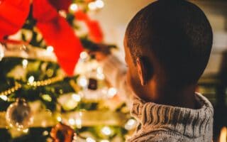 Black boy in font of christmas tree